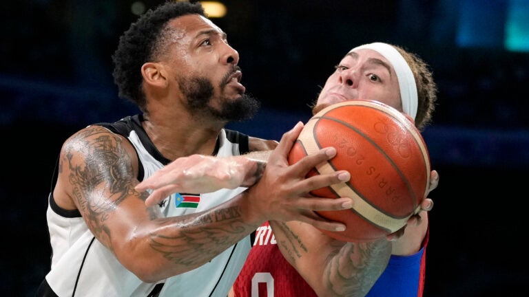 Isaiah Pineiro, right, of Puerto Rico, tries to stop a shot by Carlik Jones, of South Sudan, in a men's basketball game at the 2024 Summer Olympics in Villeneuve-d'Ascq, France.