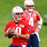 New England Patriots rookie quarterback Drake Maye (10) throws the ball as quarterback Bailey Zappe (4) looks on during OTAs at the Gillette Stadium practice field.