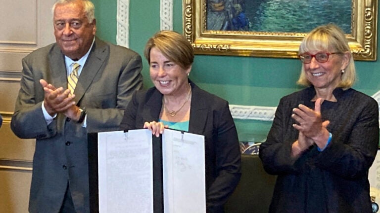 Massachusetts Gov. Maura Healey, center, shows the signed a nearly $58 billion state budget bill Monday, July 29, 2024, in Boston, that includes a plan for free community college and allows the Massachusetts Lottery to move some of its products online.