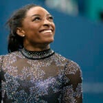 Simone Biles of United States, smiles after competing on the uneven bars during a women's artistic gymnastics qualification round at Bercy Arena at the 2024 Summer Olympics.