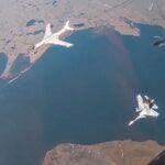 In this photo taken from video released by Russian Defense Ministry Press Service on Thursday, July 25, 2024, A H-6K long-range bomber of the Chinese air force, upper left, is seen escorted by a Su-30 fighter of the Russian air force during a joint Russia-China air patrol.