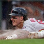 Close up of head-first slide, with clay kicking up around runner's grimaced face.