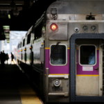 A Commuter Rail train parked alongside a train platform with commuters walking in the background